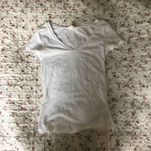  - Väldigt tight v-ringad t-shirt i vitt från H&M. Litet hål vid ena ärmen. Lite genomskinlig. Frakt tillkommer.
