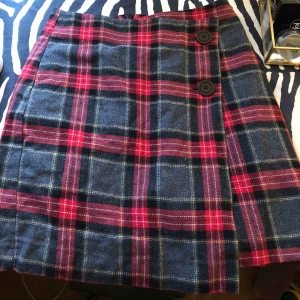  - Rutig kjol med knappar och omlott design. Köparen står för frakt!