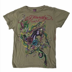Ed Hardy t-shirt - Sjukt cool ed Hardy tshirt, ikonisk y2k stil med tryck på båda sidorna! Jätte fint skick och bra kvalitet. Tar bud från 200kr. BUDGIVNINGEN AVSLUTAS ONSDAG KL 18:00