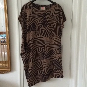  - Brun och mörkblå klänning, mycket fint skick. Endast använd en gång. Underkänning i glansigt material. Köparen står för frakten, 36 kr. Hat swish. 

