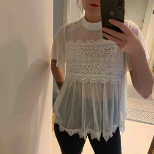  - Genomskinlig blus med spetsdetaljer och knappar i nacken