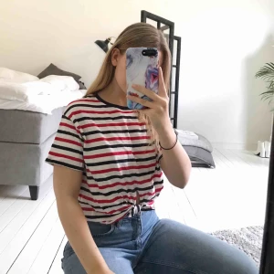  - T-shirt från Bershka i rött/vitt/blått, köpt i Spanien och passar mig som är XS/S bra. Knytet framtill gör att den får en lite ”croppad” känsla men inte så mycket att det blir en magtröja och baktill är den normallång.  