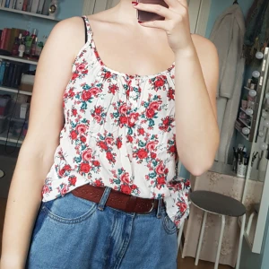  - Otroligt gulligt linne med somrigt mönster av rosor, smala reglerbara axelband, lös passform och små knappar under urringningen