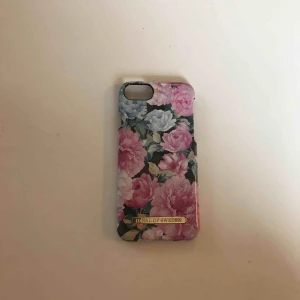  - iDeal of Sweden skal med fina blommor på. Har används flitigt, men är fortfarande i fint skick med lite repor. Köparen står för frakt. 