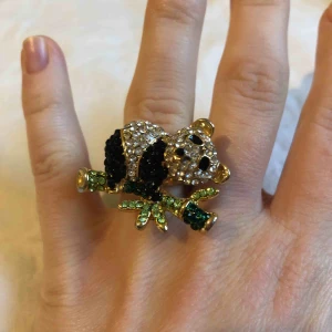  - En pandaring med glittriga stenar/pärlor där själva ringen är guldfärgad men lite avskavd färg på undersidan. Annars fint skick.