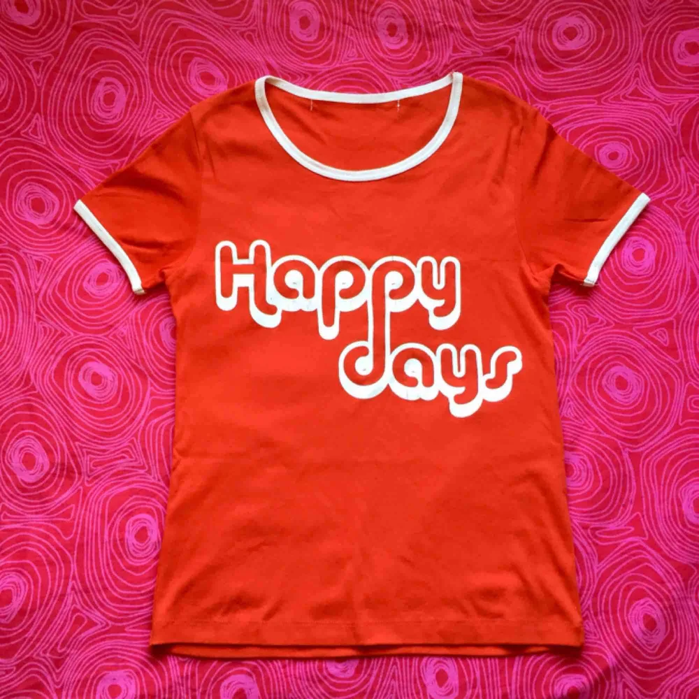 🍎 Röd t-shirt med vitt tryck där det står ’Happy days’. Obs! Det finns sprickor i texten 🍎. T-shirts.