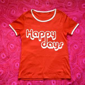 🍎 Röd t-shirt med vitt tryck där det står ’Happy days’. Obs! Det finns sprickor i texten 🍎