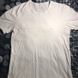 Hugo Boss T-shirt - 🤩En vit snygg och fräsch Hugo Boss T-shirt😍 Tröjan är använd några fåtal gånger, fräsch men har en liten fläck på bröstet, ej synligt när tröjan är på🙌🏼 🌟Den är skön och är perfekt att ha på sommaren eller i t.ex. skolan!☀️ 📤Köparen står för frakt, 22kr🚚