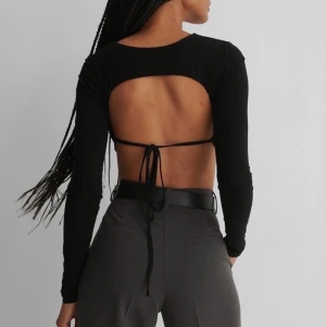 NA-KD topp med öppen rygg - En superfin långärmad tröja med knytning där bak från NA-KD. Säljer då den var för liten i armarna. Helt oanvänd och i bra skick. Lappen fortfarande på. Org pris: 200kr