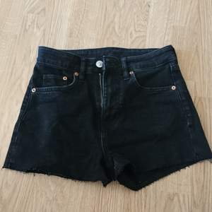A pair of tall, black, cut jeans shorts.