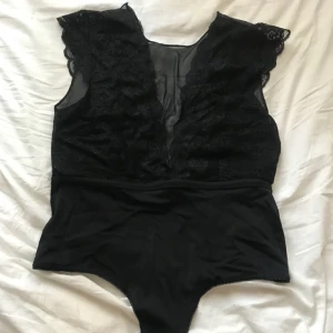  - Helt ny, lapp kvar.  Svart spets body med djup rygg.