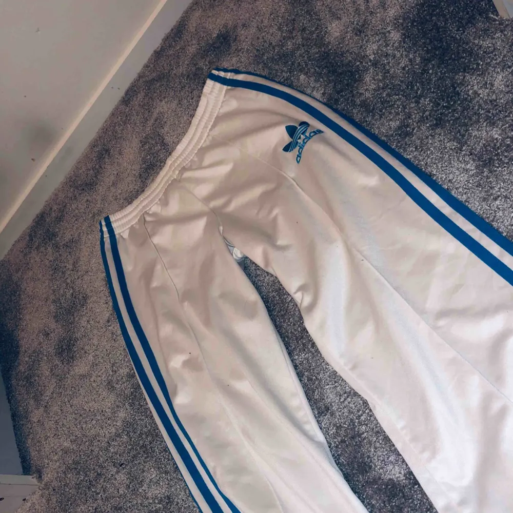 vita Adidas byxor med blåa streck, dom har en lite fläck där bak (se bild) har inte testat å tvättat så kanske går bort annars mkt fint skick✨. Jeans & Byxor.