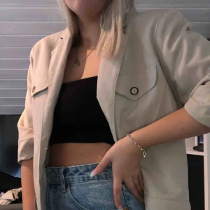  - En snygg beige blaser/kavaj som är mellanlång i armarna. 