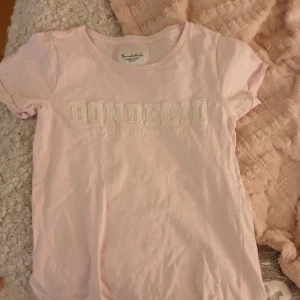  - Oanvänd bondelid t shirt i en fin rosa färg 