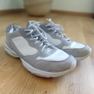  - Sneakers i blandat med vitt läder (imitation) och grå mocka (imitation) storlek 41 men små i storlek. Går ej på en 41. Passar 40. Kan fraktas då köparen står för frakten.🌷