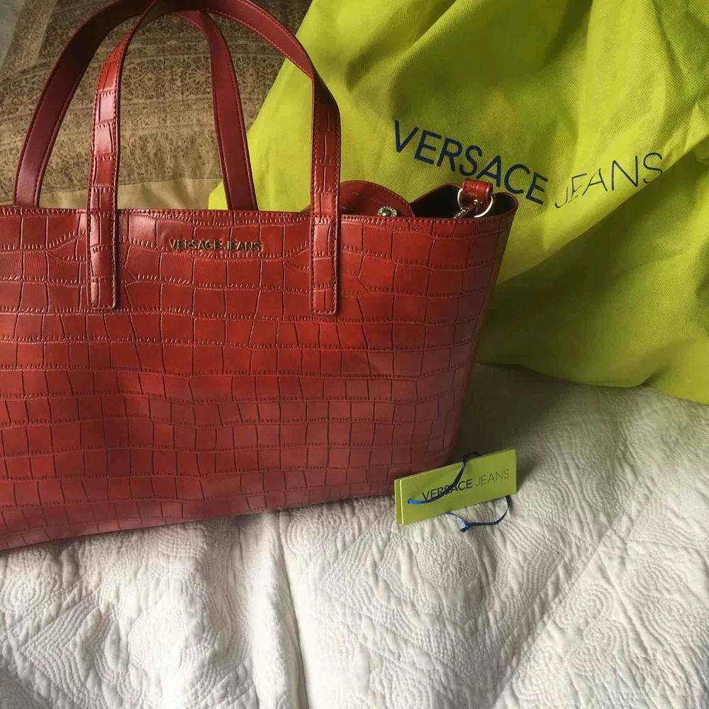 En äkta Versace väska ( med authenticity tag)  i imitations läder knappt använd och med löstagbar bagstrap samt en ”inneväska” som går att ta bort. Väskor.