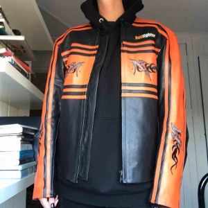  - Bikerjacka i rak modell. 90-talsstuk med tribals. Boxig passform och tjockt skinn, ganska tung. Herrmodell stl L. Aldrig använd och i jättebra skick. Är 177cm lång, stl 38/40 och den är stor på mig. Köparen betalar frakt eller möts i Gbg 