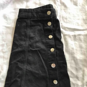  - Snygg svart kjol med knappar hela vägen. Frakt tillkommer